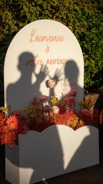 Les ombres de deux mariés sur un panneau de bienvenue fleuri. Publication Instagram (nouvel onglet).
